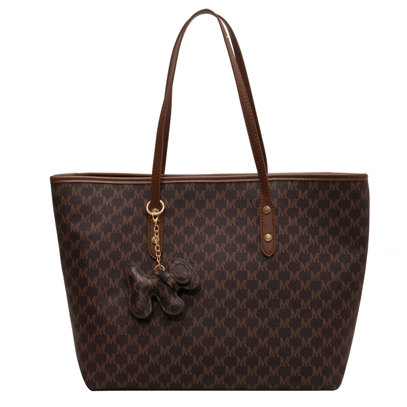 Dark patterned tote with brown trim and hanging charm